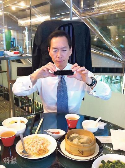 行會成員陳智思去食飯，拎起手機影相係做紀錄，因為有NGO搞活動，喺指定餐廳點選指定菜式，就會自動捐兩蚊做善事。（黃振豪攝）