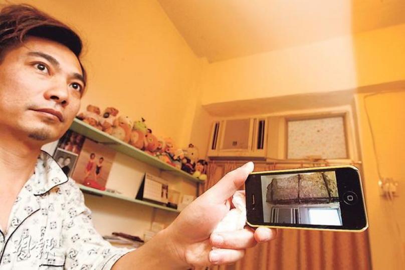 住在西環新安大廈7樓的許先生,月前家中冷氣機對上的一幅石屎牆突然倒塌(見圖中iPhone屏幕),他質疑這與港鐵工程有關,但由於擔心調查需時,最終選擇自行維修。(李紹昌攝) 住在西環新安大廈7樓的許先生,月前家中冷氣機對上的一幅石屎牆突然倒塌(見圖中iPhone屏幕),他質疑這與港鐵工程有關,但由於擔心調查需時,最終選擇自行維修。(李紹昌攝)