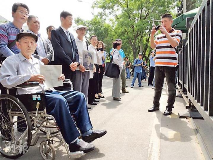 中國勞工代表張士傑（圖左坐輪椅者）在日本使館門口準備遞交致日本首相安倍的信函。（楊歡攝）