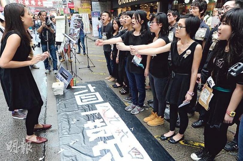 一批大專生噚日趁公眾假期，喺旺角行人專用區為六四事件「報哀音」，吸引唔少包括內地自由行嘅途人圍觀。（尹錦恩攝）