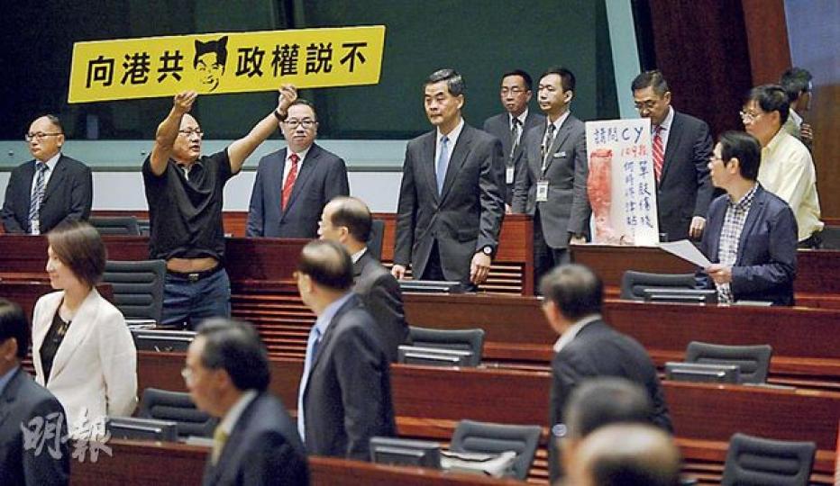 昨日答問大會中,人民力量陳偉業向特首梁振英追問菲律賓人質事件,其間大罵梁振英「狗樣」,及後被趕離議事廳。圖為昨日梁進場時,陳舉牌抗議。(余俊亮攝) 昨日答問大會中,人民力量陳偉業向特首梁振英追問菲律賓人質事件,其間大罵梁振英「狗樣」,及後被趕離議事廳。圖為昨日梁進場時,陳舉牌抗議。(余俊亮攝)