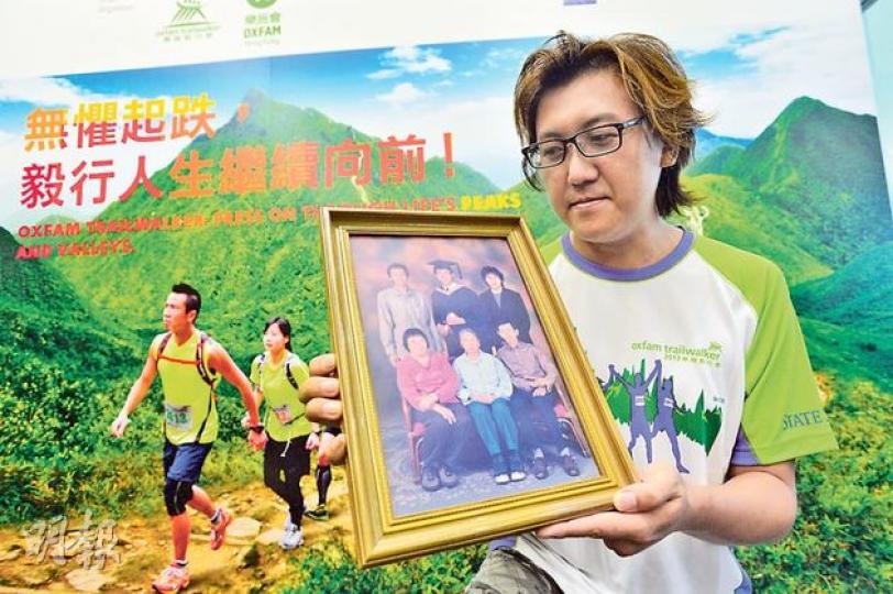 今年第3年與父及弟組隊參加毅行者的謝志堅（圖）說，過去3年向菲律賓爭取公道好比毅行者最艱辛的路段，「行極都未完」，但近日談判有進展，令他見到曙光，覺得終點在望。圖為他展示昔日的全家福。（鄧宗弘攝）