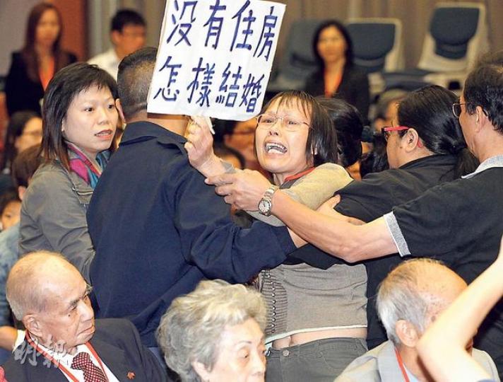出席人口政策諮詢會的張女士(持紙牌者),因情緒激動大呼「沒有住房怎樣結婚」的口號,最初被認為是擾亂秩序遭帶離會場;其後主持終容許她發問。她表示,因樓價高企,兩名兒子結婚都沒有錢買樓,只能一家3戶都住在300呎的房子,要求政府調低居屋價格。(李紹昌攝)「關注中港家庭權利聯席」10多名成員,昨在人口政策諮詢會開始前,於門前向政務司長林鄭月娥(右)遞交請願信,希望政府取回單程證審批權,盡快讓港人在內地的家人來港團聚。(李紹昌攝)(明報製圖) 出席人口政策諮詢會的張女士(持紙牌者),因情緒激動大呼「沒有住房怎樣結婚」的口號,最初被認為是擾亂秩序遭帶離會場;其後主持終容許她發問。她表示,因樓價高企,兩名兒子結婚都沒有錢買樓,只能一家3戶都住在300呎的房子,要求政府調低居屋價格。(李紹昌攝)「關注中港家庭權利聯席」10多名成員,昨在人口政策諮詢會開始前,於門前向政務司長林鄭月娥(右)遞交請願信,希望政府取回單程證審批權,盡快讓港人在內地的家人來港團聚。(李紹昌攝)(明報製圖)