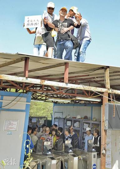 將軍澳日出康城地盤工人向承建商追討欠薪，有情緒激動的工人爬上鐵皮屋頂抗爭，一度企圖跳下，同事即出手阻擋，其間其他工人在鐵皮屋內與勞工處職員商討。（劉焌陶攝）昨早勞資雙方在勞工處人員調解下談判，其間工程二判淮輝工程的代表（右）直言無法支付欠薪，並即將為公司申請破產。（劉焌陶攝）