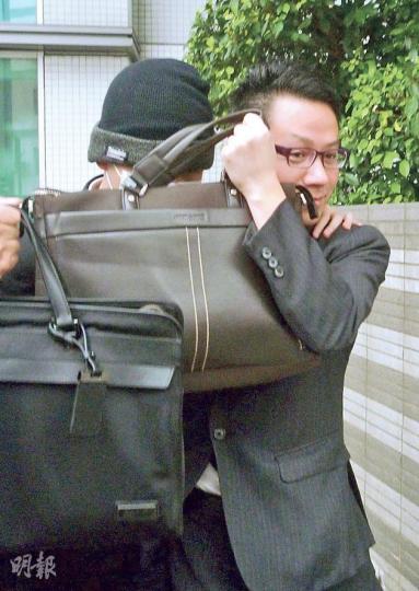 被告劉家馳（戴帽者）昨被判入勞教中心，但獲准保釋等候上訴，離開法庭時戴上口罩，再由兩名男士以手提包遮臉護送離開。（何海棠攝）