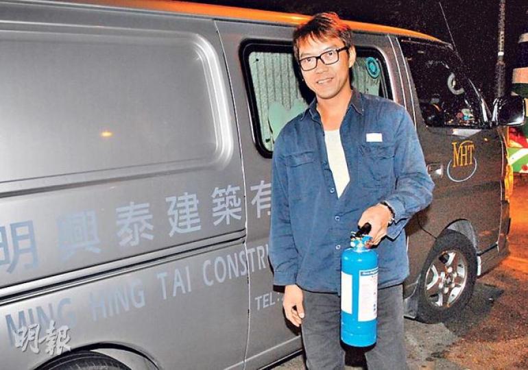 獲網民大讚是救火英雄的客貨車司機龍先生，在客貨車旁展示曾用於救火的滅火筒，並謙稱只是盡一點力幫人。（伍浦鋒攝）