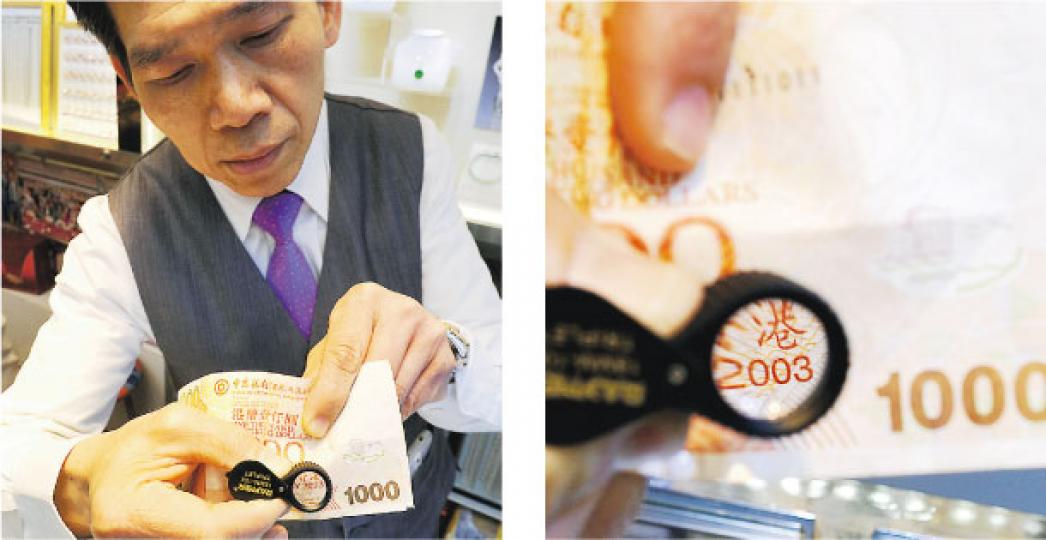 深水埗美麗華珠寶金行的總行營業部主任麥志偉，用放大鏡檢驗剛收來中銀2003年版千元鈔票，字樣清晰可見。（鍾炳然攝）