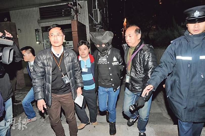 昨晚深夜，探員將其中22歲被捕大學生以黑布蒙頭，押返西灣河街後巷縱火案現場調查。（樊銳昌攝）