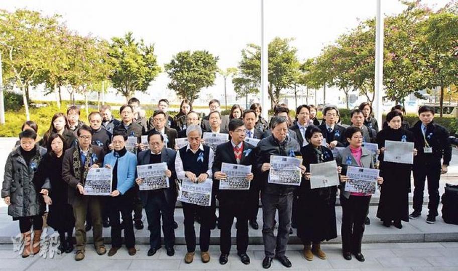立法會昨日辯論由公民黨梁家傑提出的新聞自由議案，一批明報現職及前任員工，早上到立法會外派發藍色絲帶，邀請各黨派議員即場扣上，支持新聞自由。其中泛民議員（持報紙者）響應活動，並在昨晨集體到立法會門外接受藍絲帶，並自備前日報道更換總編輯事件的《明報》默站一分鐘，以示支持。（李澤彤攝）