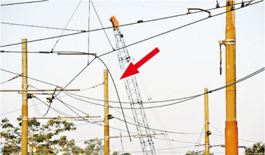 輕鐵天水圍塘坊村站範圍的一段架空電纜，疑因絕緣體損毁致一條電纜鬆脫垂下（箭嘴示），電纜觸碰到途徑列車，令車頂出現火花及冒煙而需暫停行駛。（蔡方山攝）