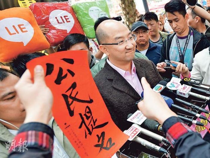 政制及內地事務局長譚志源昨日到維園年宵市場向市民派發政改宣傳單張，其間有市民指着他，高呼要求公民提名。（盧翊銘攝）