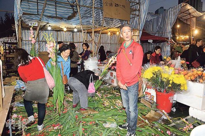 檔主梁先生（圖右紅衣者）嘆謂天氣較往年熱，劍蘭多凋謝，導致滯銷，只好放到地上，任市民撿拾。（蔡方山攝）