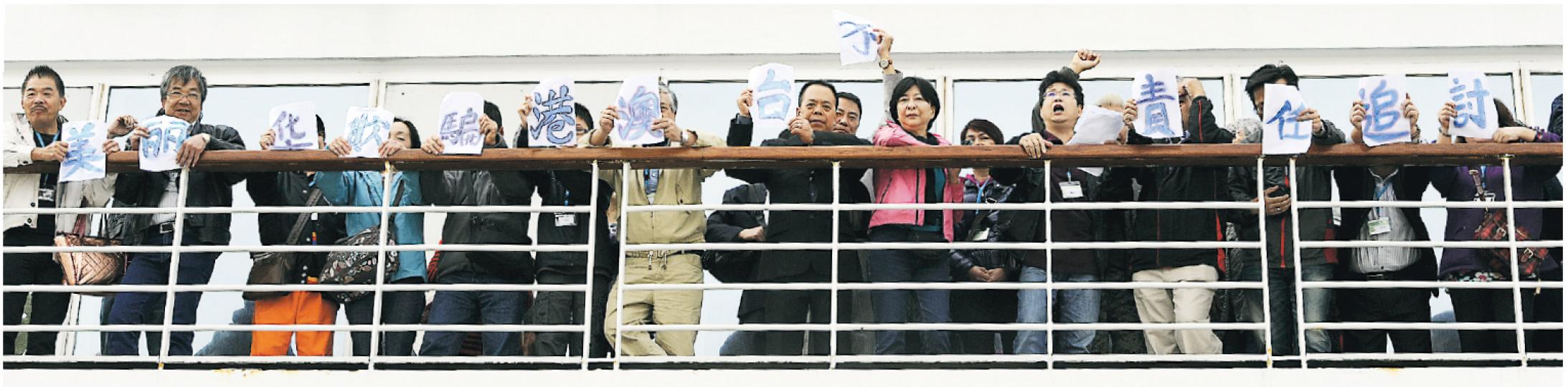 逾300名郵輪客昨晨起在船上抗議，不滿行程「貨不對辦」，拒絕落船，並在船上舉起標語抗議及叫口號，受影響旅客包括民建聯立法會議員蔣麗芸（前排右六，粉紅衣者）。（蔡方山攝）船上抗議13小時後，部分旅客晚上10時許離船，前往附近酒店與旅行社商討，其間更出示勝利手勢。（葉家豪攝）
