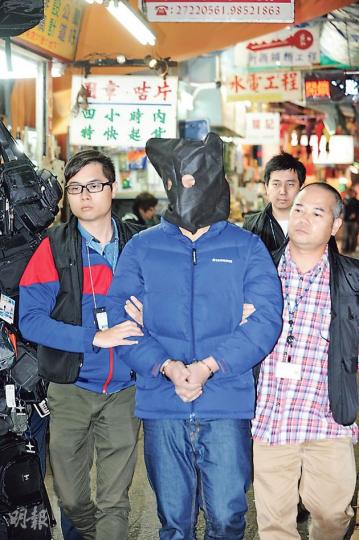 警方破獲去年底在尖沙嘴發生的兌換店女職員遇劫案件，在粉嶺拘捕兩名涉案青年；昨午探員把疑犯黑布蒙頭押返案發現場調查。（樊銳昌攝）