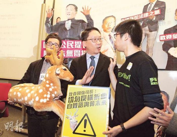 律政司長袁國強(中)昨出席學聯大專政改論壇與過百學生辯論政改,有同學準備紙板公仔「招呼」他。學聯秘書長陳樹暉(右)向袁送上鹿公仔,勸對方正視民意,勿「指鹿為馬」,但袁以官員不收禮物為由而未有接收。(李澤彤攝) 律政司長袁國強(中)昨出席學聯大專政改論壇與過百學生辯論政改,有同學準備紙板公仔「招呼」他。學聯秘書長陳樹暉(右)向袁送上鹿公仔,勸對方正視民意,勿「指鹿為馬」,但袁以官員不收禮物為由而未有接收。(李澤彤攝)