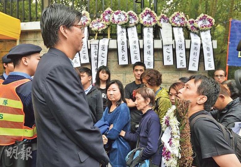 手持花牌的港視導演蔡錦源（前右），昨被掛上「行政長官辦公室」職員證件男子（前左）及民安隊成員以「手持示威品」為由拒諸門外，後來即使提出放下示威品要求內進，禮賓府亦表明「不歡迎」他入內。（余俊亮攝）
