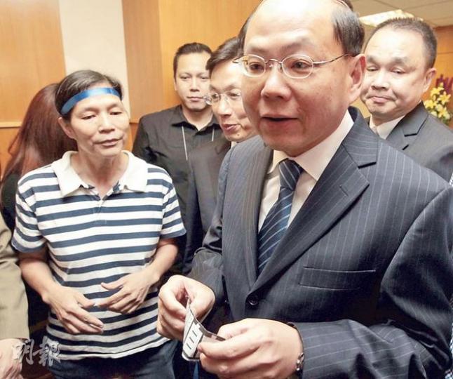 「女長毛」雷玉蓮（左）昨在南區區議會上向警務處長曾偉雄（前右）遞上貼有「新聞自由」四字之藍絲帶，不滿他早前指劉進圖遇襲案「無直接證據顯示與新聞工作有關」之言論。（郭慶輝攝）