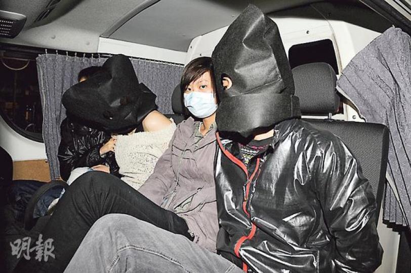 探員在大埔懷義街拘捕兩名涉嫌販毒的同性「毒鴛鴦」，打扮較中性的女子（右）連同其身穿露肩裝的女友（左），被探員黑布蒙頭帶署扣查。（蔡方山攝）
