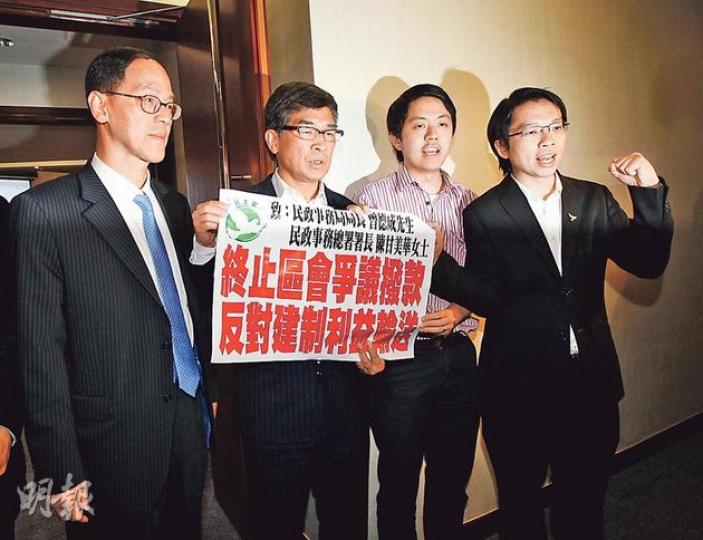 區議員許智峯（右二）喺黨友兼立法會議員單仲偕（左二）、吳兆康（右一）陪同下，向民政局長曾德成（左一）遞請願信，要求當局介入區議會《基本法》宣傳撥款事件。（李紹昌攝）