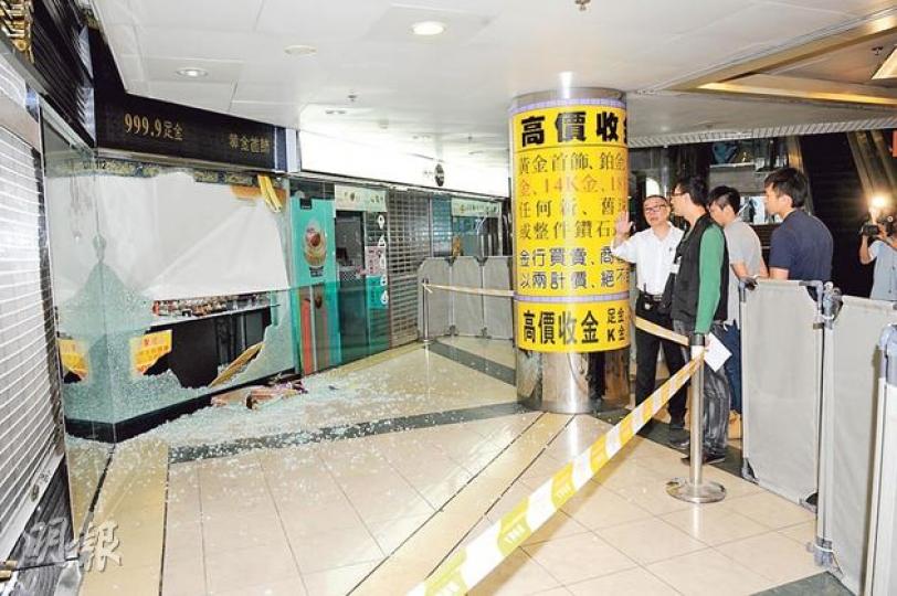 藍田啟田商場一間金舖昨晨被爆竊，兩賊用鐵槌擊碎櫥窗玻璃，掠去一批黃金擺設。圖為商場保安（白衣者）向探員講述案發過程。（蔡方山攝）