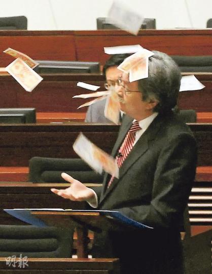 立法會會議舉行期間,議員梁國雄趁財政司長曾俊華(圖)發言時上前,向曾俊華擲陰司紙,抗議政府忽略老人福利,部分陰司紙散落曾的頭上。(李紹昌攝) 立法會會議舉行期間,議員梁國雄趁財政司長曾俊華(圖)發言時上前,向曾俊華擲陰司紙,抗議政府忽略老人福利,部分陰司紙散落曾的頭上。(李紹昌攝)