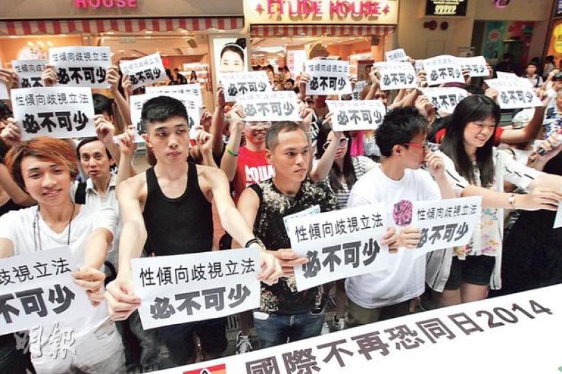 爭取性傾向歧視立法陣線昨在銅鑼灣舉行「國際不再恐同日」街頭活動，男同志阿永（前排左二）憶述中學時向同窗坦白性傾向，卻遭排擠及歧視，創傷至今未完全平復。（李紹昌攝）圖中的「歧視暗黑隧道」藝術裝置有兩個出口，分別是較高的「直人」出口及較低的「同志」出口，象徵同志在社會上仍「低人一等」、備受歧視，藉此促請政府盡快就性傾向歧視立法。（李紹昌攝）