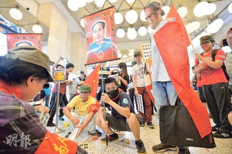 10多名網民昨持「讓遊客與旅遊巴佔領北角」等標語，反對自由行來港。部分網民身披國旗、手持毛澤東肖像，沿着北角渣華道向商店職員叫嚷，更於新光戲院內假裝便溺，諷刺早前商經局長蘇錦樑的包容論。（鄧宗弘攝）