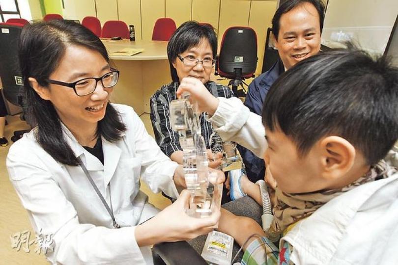 需插喉用呼吸機維生的浲浲（右）在大口環根德公爵夫人兒童醫院學會走路、發音、吞咽等生活技能，最終能出院回家及上學。左起：該院兒童及青少年科顧問醫生李素輪、助理社會工作主任張秀玲、護士主任黃子明。（李紹昌攝）