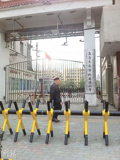 離爆炸地約200米的烏魯木齊市外語小學門外設有3道護欄，接送學生的車只能停泊在近百米外。（明報記者攝）烏魯木齊市面昨日氣氛凝重，行人稀少，圖為軍警在該市地標人民廣場戒備巡邏。（明報記者攝）