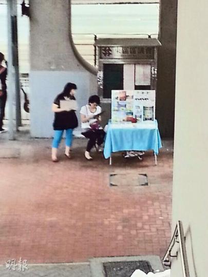 本報記者昨在北角糖水道發現「全能神」的攤檔,其中一名中年婦人(左)前來問記者是否信基督教,又把教會去年於報章刊登的廣告派給記者。(明報記者攝) 本報記者昨在北角糖水道發現「全能神」的攤檔,其中一名中年婦人(左)前來問記者是否信基督教,又把教會去年於報章刊登的廣告派給記者。(明報記者攝)