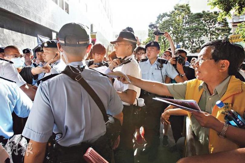 愛港之聲昨日在維園附近天后入口擺街站宣揚「六四無屠城」說法，警方排成多重人鏈隔開愛港之聲主席高達斌（右黃色背心者）及指罵他們的市民（左戴口罩者）。（林俊源攝）一名反愛港之聲的男子涉嫌行為不檢，被警方鎖上手扣帶走。（林俊源攝）