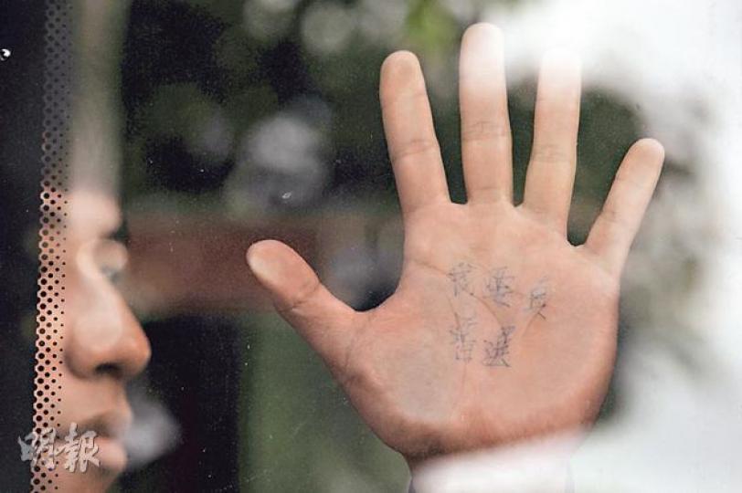 有佔中被捕人登上警察安排的旅遊巴後，展示手掌上的「我要真普選」字句。（葉家豪攝）