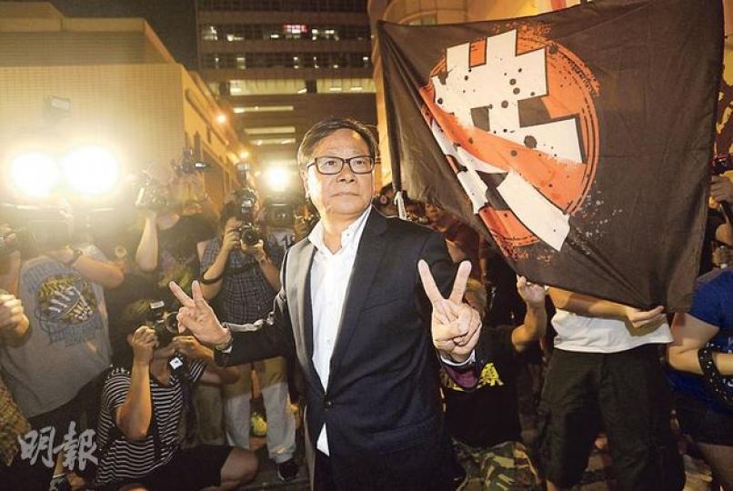 黃毓民前日在立法會向特首梁振英擲水杯，黃昨晚自行到中區警署協助調查，進入後即被拘捕。圖為他進入警署前，向支持者展示勝利手勢。（余俊亮攝）