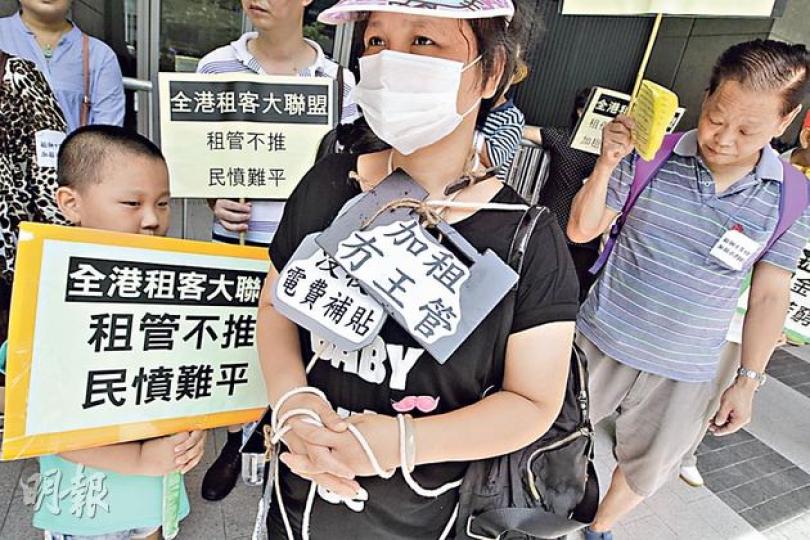 大聯盟成員用麻繩掛上示威標語，纏着全身，寓意遭租金綑綁，要求政府盡快落實租金管制，保障租客權益。（李澤彤攝）