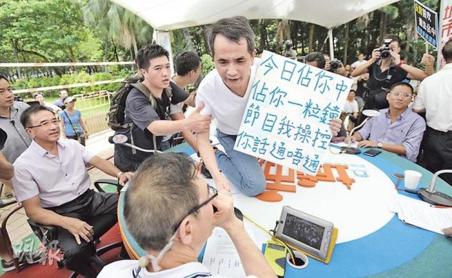 《城市論壇》昨日直播開始未夠兩分鐘,一名中年男子手持反佔中標語衝上嘉賓枱,節目被打斷超過1分鐘。主持謝志峰(圖下方)隨即要求警員帶走該名男子。(余俊亮攝) 《城市論壇》昨日直播開始未夠兩分鐘,一名中年男子手持反佔中標語衝上嘉賓枱,節目被打斷超過1分鐘。主持謝志峰(圖下方)隨即要求警員帶走該名男子。(余俊亮攝)