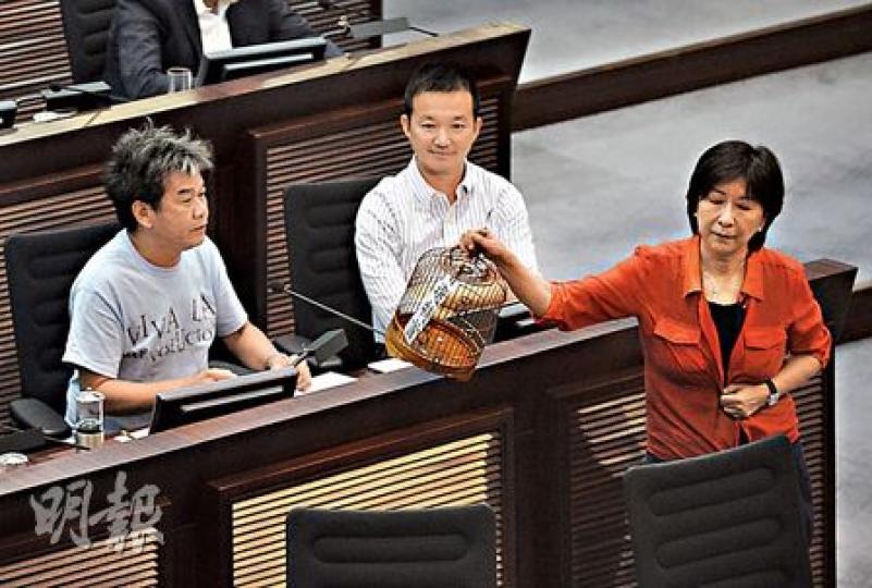 社民連梁國雄(左)發言時,民建聯蔣麗芸(右)突然行去佢面前,拎走枱面上嘅鳥籠道具。(余俊亮攝)蔣麗芸拎起個鳥籠轉身走,長毛一時間都反應唔切,只能大聲投訴,旁邊嘅陳志全都忍唔住笑。(余俊亮攝) 社民連梁國雄(左)發言時,民建聯蔣麗芸(右)突然行去佢面前,拎走枱面上嘅鳥籠道具。(余俊亮攝)蔣麗芸拎起個鳥籠轉身走,長毛一時間都反應唔切,只能大聲投訴,旁邊嘅陳志全都忍唔住笑。(余俊亮攝)