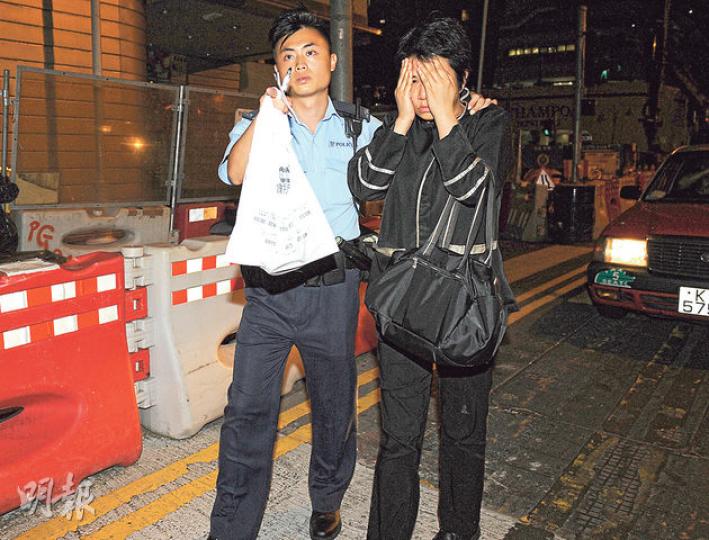 在博藝會擔任兼職侍應的女子涉嫌偷酒被捕,她當時仍身穿制服(右),警員以膠袋盛載着涉案的酒(左)。(蔡方山攝) 在博藝會擔任兼職侍應的女子涉嫌偷酒被捕,她當時仍身穿制服(右),警員以膠袋盛載着涉案的酒(左)。(蔡方山攝)