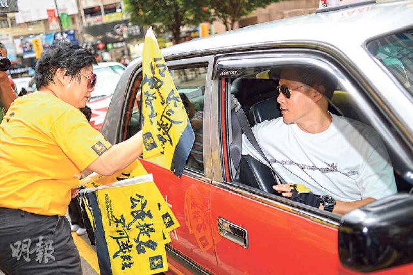 人民力量成員譚香文(左)昨向的士司機派發寫有支持公民提名標語的旗幟,並呼籲的士司機把旗幟安裝於車窗上。(葉家豪攝) 人民力量成員譚香文(左)昨向的士司機派發寫有支持公民提名標語的旗幟,並呼籲的士司機把旗幟安裝於車窗上。(葉家豪攝)
