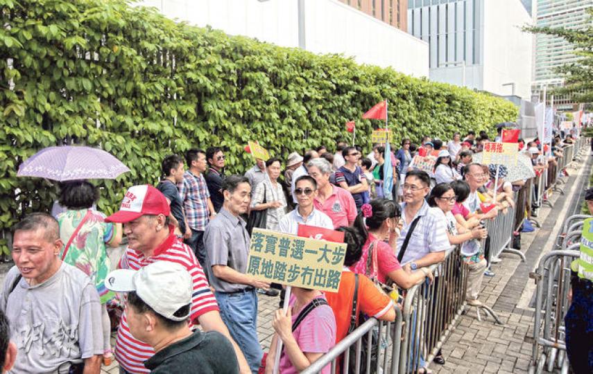 幾百個支持政府嘅市民，噚日下午喺逾30℃烈日下，於政總外請願，要求落實一人一票普選，不過佢哋被指聲浪太大，嘈住梁振英同記者講話。（李澤彤攝）
