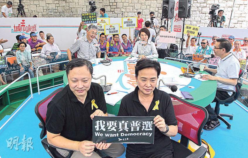 佔中發起人戴耀廷（前左）及民主黨主席劉慧卿（前右）昨出席《城市論壇》，舉起「我要真普選」標語以表達對中央「落閘」的不滿。劉認為政改第二輪諮詢討論空間不大，與出席的民建聯副主席李慧琼（後中）激辯。（李澤彤攝）