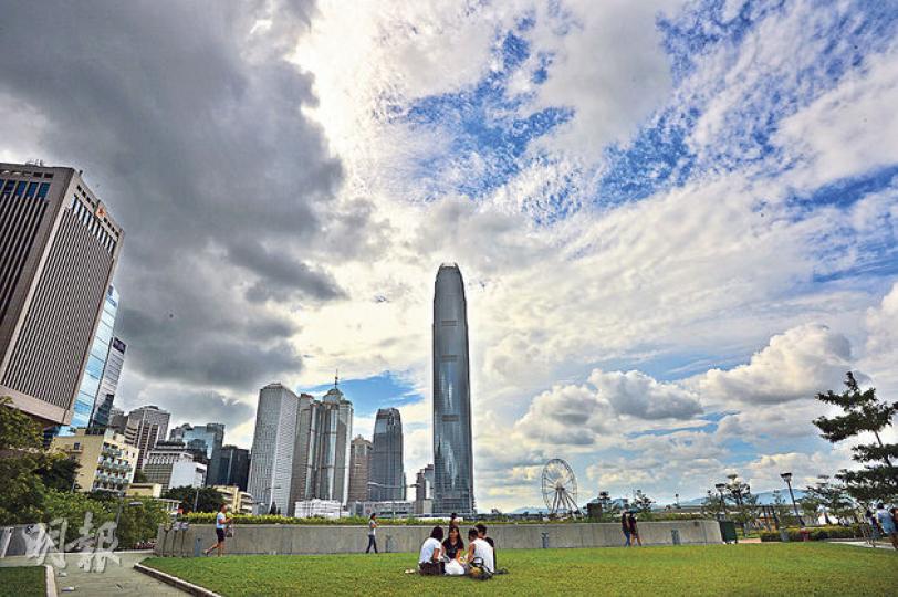 天文台昨發出1號戒備信號，有市民毋懼風雨前往添馬公園草地休憩，半邊天烏雲，半邊藍天，別有一番景致。（葉家豪攝）