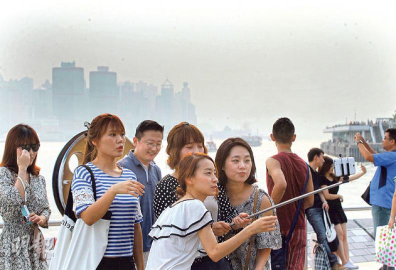 受熱帶風暴「鳳凰」橫流影響,本港昨午有煙霞,能見度低,從尖沙嘴星光大道望向維港對岸,天空灰濛濛,但遊客自得其樂,繼續玩自拍。(李紹昌攝) 受熱帶風暴「鳳凰」橫流影響,本港昨午有煙霞,能見度低,從尖沙嘴星光大道望向維港對岸,天空灰濛濛,但遊客自得其樂,繼續玩自拍。(李紹昌攝)