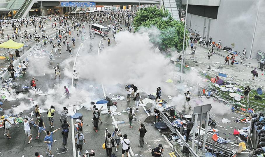 「和平佔中」啟動,號召群眾率先包圍政府總部,令添馬政總外的干諾道中成為昨日示威者的主戰場。防暴警察在政總(圖右方)外築起重重防線,大批示威者則在干諾道中集結堵塞馬路,不斷衝擊警方防線。警方在近6時舉起黑色警告,不消一會即打響第一枚催淚彈,迫使群眾退回海富中心。(胡景禧攝)昨日市民在金鐘集會時,一支警車隊沿紅棉路北行駛到金鐘道,其間遭一批示威者用鐵馬和雪糕筒阻截,警察即時下車,手持警棍逼示威者退回路面。(劉峻陶攝)今日凌晨時仍有市民留守中環,部分人手牽手坐在路面靜坐。(鄧宗弘攝) 「和平佔中」啟動,號召群眾率先包圍政府總部,令添馬政總外的干諾道中成為昨日示威者的主戰場。防暴警察在政總(圖右方)外築起重重防線,大批示威者則在干諾道中集結堵塞馬路,不斷衝擊警方防線。警方在近6時舉起黑色警告,不消一會即打響第一枚催淚彈,迫使群眾退回海富中心。(胡景禧攝)昨日市民在金鐘集會時,一支警車隊沿紅棉路北行駛到金鐘道,其間遭一批示威者用鐵馬和雪糕筒阻截,警察即時下車,手持警棍逼示威者退回路面。(劉峻陶攝)今日凌晨時仍有市民留守中環,部分人手牽手坐在路面靜坐。(鄧宗弘攝)