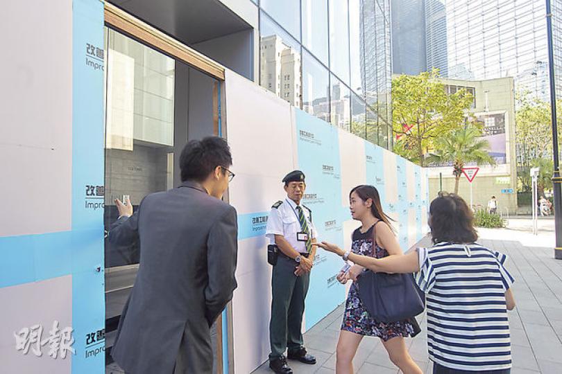 昨日中環和金鐘多幢商業大廈及銀行總行加強保安,如圖中建設銀行大廈門外便架起木板以防衝擊,門外有保安把守。圖為大廈職員昨在門外指引上班者入內。(明報記者攝) 昨日中環和金鐘多幢商業大廈及銀行總行加強保安,如圖中建設銀行大廈門外便架起木板以防衝擊,門外有保安把守。圖為大廈職員昨在門外指引上班者入內。(明報記者攝)