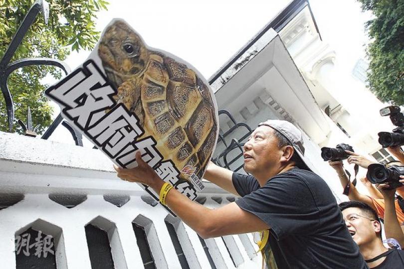 泛民飯盒會10多名議員昨日帶同象徵「龜縮」的烏龜紙牌到禮賓府,表達不滿特首梁振英連日未有面向公眾,僅在禮賓府辦公,透過電視「讀稿」講話與市民溝通。圖為立法會議員李卓人高舉烏龜紙牌。(李紹昌攝) 泛民飯盒會10多名議員昨日帶同象徵「龜縮」的烏龜紙牌到禮賓府,表達不滿特首梁振英連日未有面向公眾,僅在禮賓府辦公,透過電視「讀稿」講話與市民溝通。圖為立法會議員李卓人高舉烏龜紙牌。(李紹昌攝)