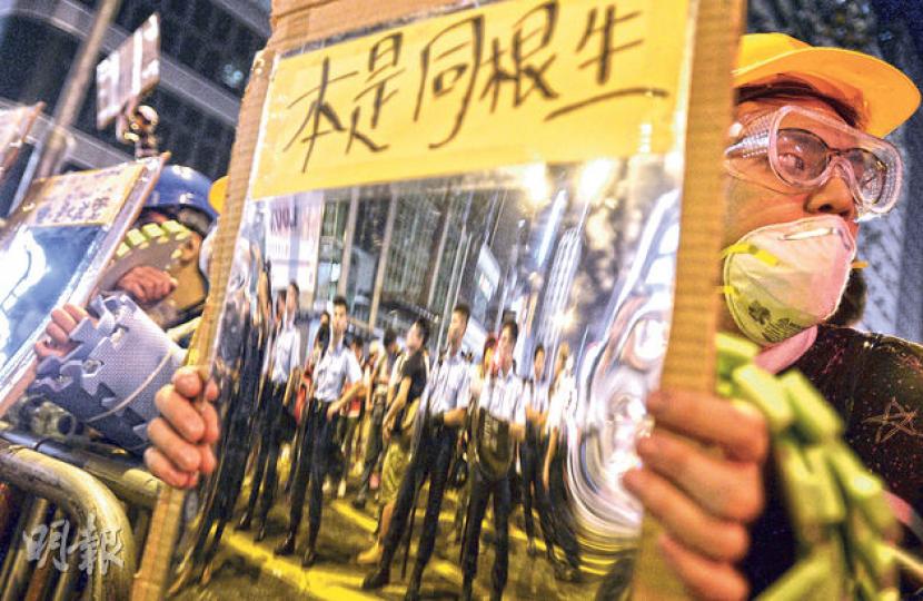 有市民昨晚在旺角對着警員,舉起由反光物料製成的示威「鏡牌」,寫有「本是同根生」等字句。(盧翊銘攝) 有市民昨晚在旺角對着警員,舉起由反光物料製成的示威「鏡牌」,寫有「本是同根生」等字句。(盧翊銘攝)