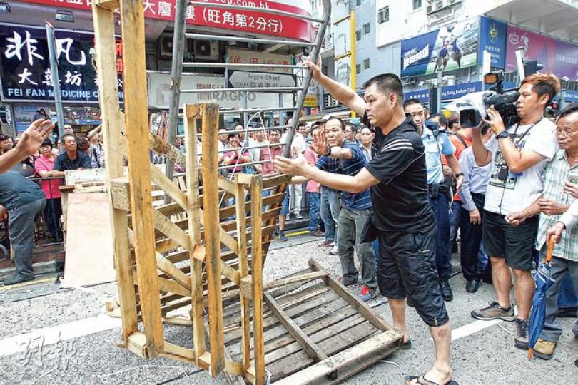 多名男子昨日自行到旺角清理路障,圖中男子拿起鐵馬及木架移離路面。(李紹昌攝) 多名男子昨日自行到旺角清理路障,圖中男子拿起鐵馬及木架移離路面。(李紹昌攝)