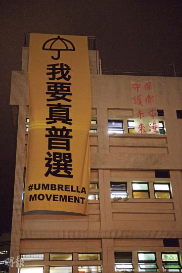 自獅子山上大型「我要真普選」標語被拆除後，多個地方相繼懸掛巨幡，繼城大、科大、港大，威爾斯醫院醫科生宿舍外牆亦出現大型黃色直幡，同樣是「我要真普選」大字加上雨傘圖案，另有一幅標語寫有「保衛香港，守護未來」，至昨傍晚仍未拆除。醫科生宿舍屬中大醫學院管理，醫學院發言人表示，尊重學生言論及表達意見自由，但巨型黃色直幡懸掛的位置非常當風，醫院保安組擔心會對途人及行經車輛造成危險。經多個單位商討後，為安全起見，學生明白並已同意把直幡除下；至於其他小型直幡、告示及標語則完全不受影響。（劉焌陶攝）
