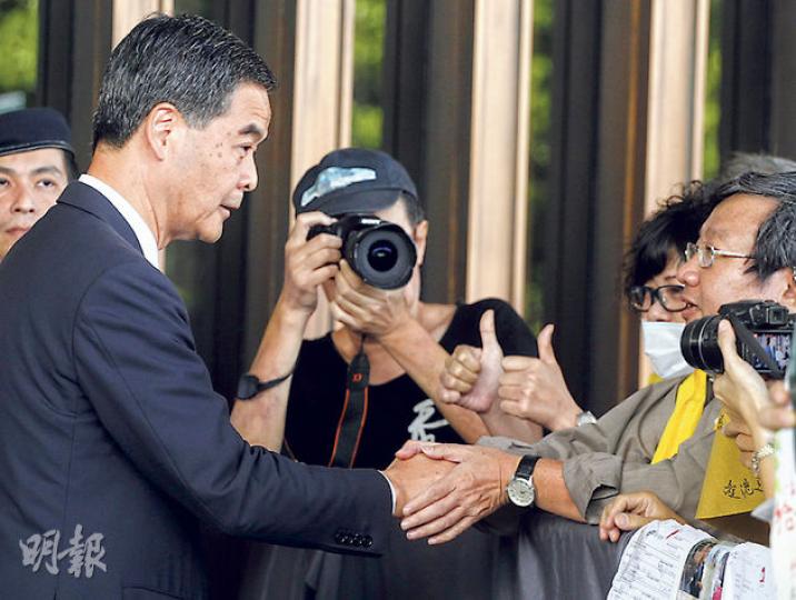 愛港之聲10多名成員昨晨手持國旗及區旗，在行政會議召開前到特首辦請願，要求政府就佔領行動盡快清場。行政長官梁振英（左）接收他們的請願信，並與愛港之聲主席高達斌（右）握手，另有成員對梁豎起拇指。（李紹昌攝）（明報製圖）
