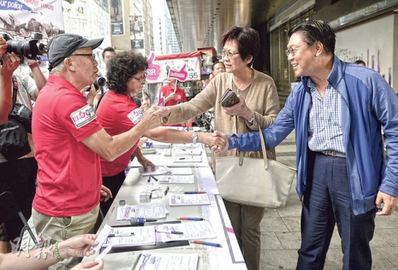 前商務及經濟發展局長馬時亨（右）昨到中環畢打街的保普選反佔中大聯盟街站簽名，其間與街站職員握手。馬時亨8月時曾表示，自己不會簽名支持反佔中行動，以免令社會撕裂及兩極化。（余俊亮攝）